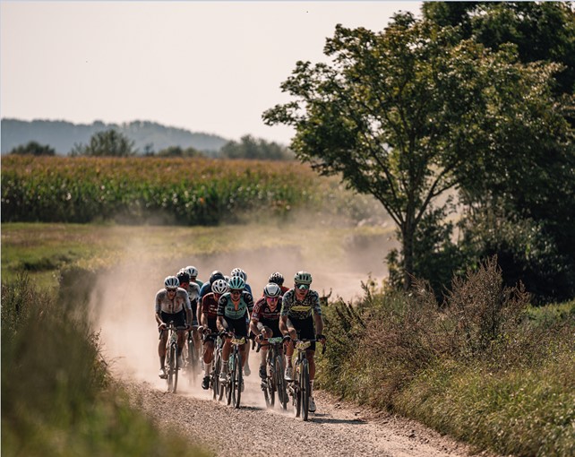 Wielrenners fietsen over een veldweg in het heuvellandschap